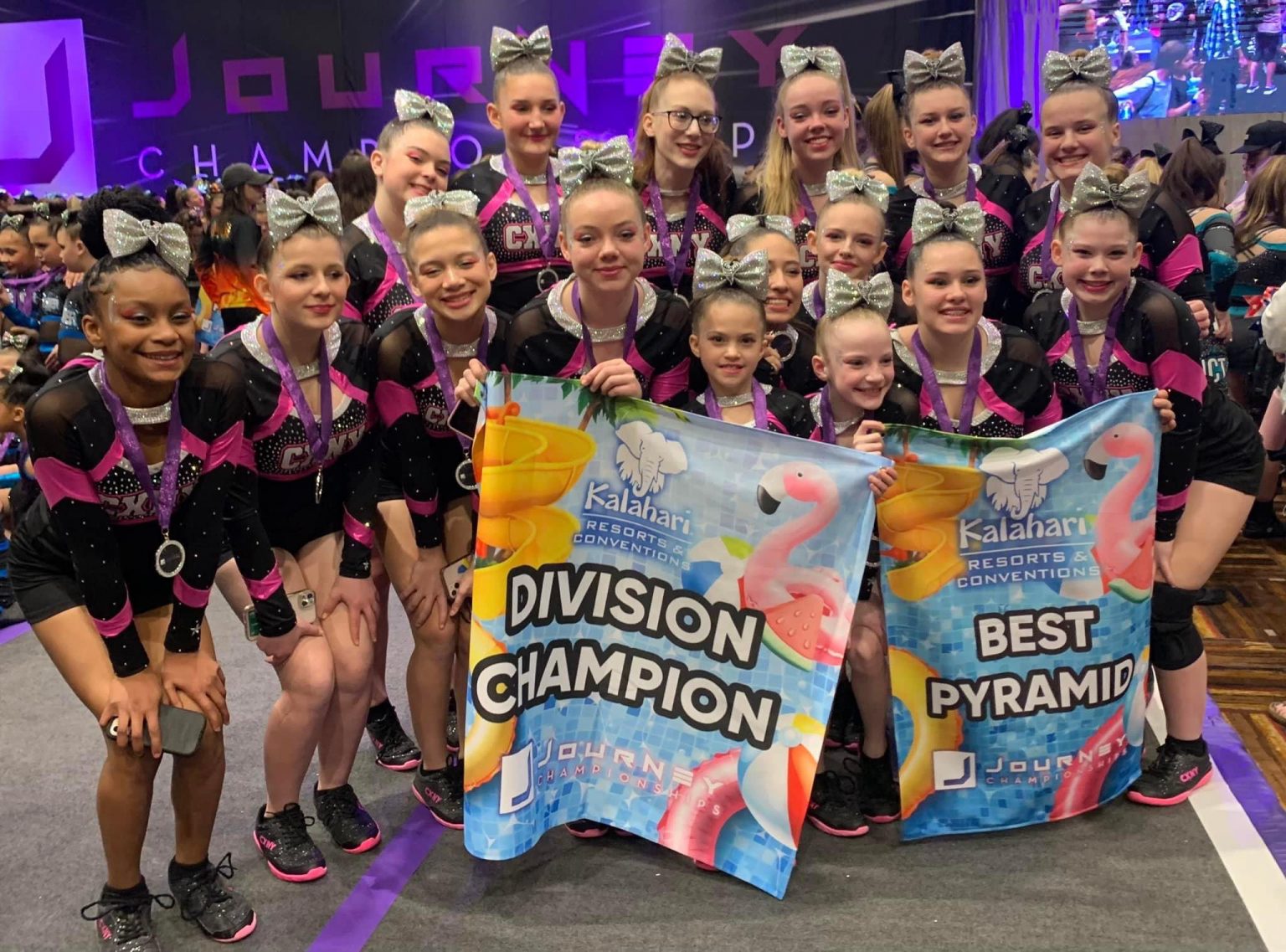 Cheerleading team celebrating their championship win with banners.