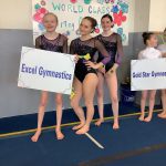 Gymnasts holding team signs at competition.