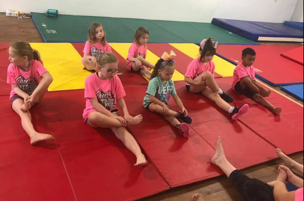 Children sitting on mats in a gym class.