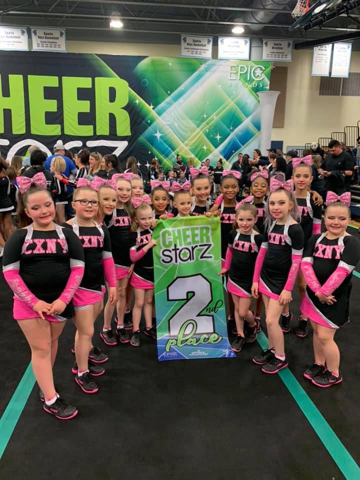 Young cheerleaders posing with a large 'Level 2' banner.